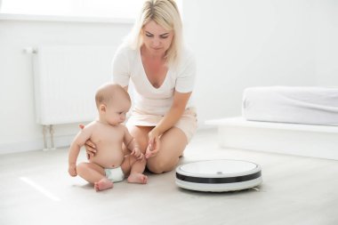 Bebeğin yanında robot süpürge var.