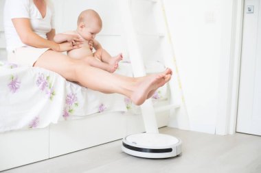 Bebeğin yanında robot süpürge var.
