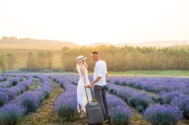 Lavanta tarlasında bavulu olan kadın ve erkek.,