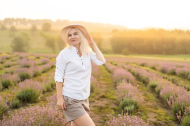 Lavanta tarlasında duran genç bir kadın ve arka planda gün doğumu.