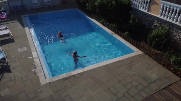 A mãe com a filha diverte-se na piscina. A mãe brinca com a criança. A família desfruta de férias de verão em uma piscina. — Vídeo de Stock