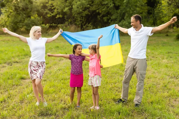 Flaga Ukraina w rękach dziewczynki na polu. Dziecko nosi trzepoczącą niebiesko-żółtą flagę Ukrainy na tle pola. — Zdjęcie stockowe