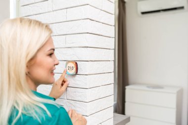 Gülümseyen Kadın Isıtma Sisteminde Termostatı Ayarlıyor