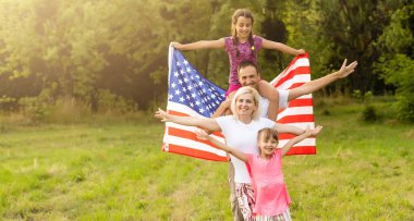 Gün batımında Amerika bayrağıyla mutlu bir aile.