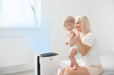 Anne ve bebek evde hava temizleyicinin yanında..