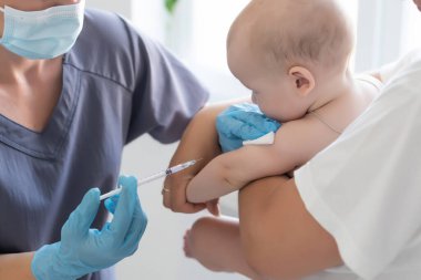 Çocuk doktoru küçük çocuğa aşı yapıyor.