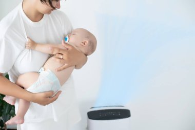 Anne ve bebek evde hava temizleyicinin yanında.