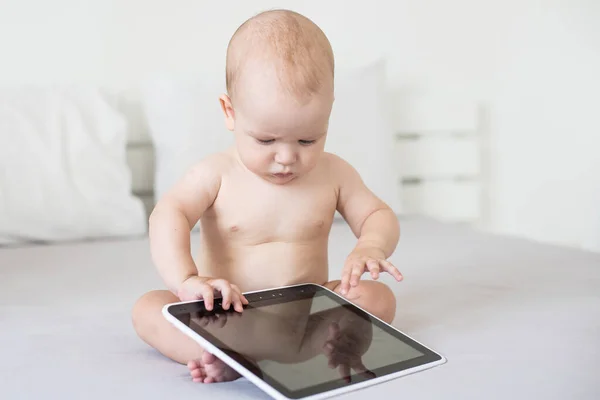 Een baby van zes maanden met een tablet computer, naar het scherm kijkend, thuis — Stockfoto