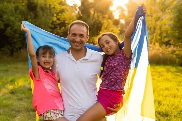 Vlajka Ukrajiny v rukou malé holčičky v terénu. Dítě nese vlající modrou a žlutou vlajku Ukrajiny na pozadí pole. — Stock fotografie