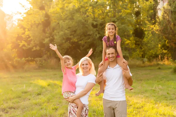 Famille heureuse profitant de la vie ensemble au pré en plein air. — Photo