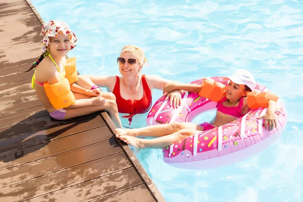 Familia feliz jugando en la piscina. Concepto vacaciones de verano — Foto de Stock