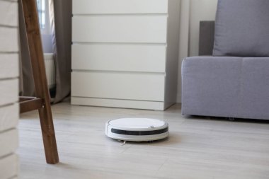 Akıllı Ev. Elektrikli süpürge robotu oturma odasında ahşap zeminde koşar.