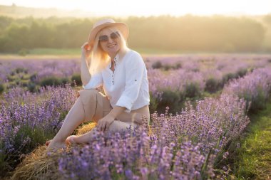 Lavanta tarlasında duran genç bir kadın ve arka planda gün doğumu.