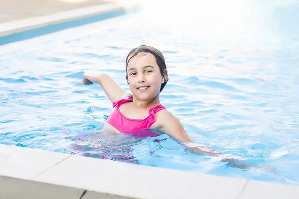 Счастливая маленькая девочка развлекается в бассейне в купальнике. — стоковое фото