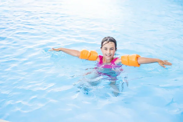 Jolie petite fille nageant dans la piscine extérieure et s'amuser — Photo