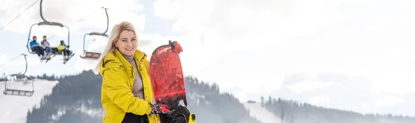 Mujer joven con snowboard en la ladera de la colina en el resort de invierno —  Fotos de Stock