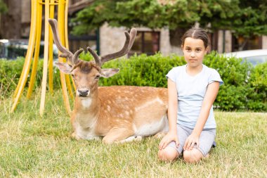 Küçük kız bir ren geyiğiyle duruyor.