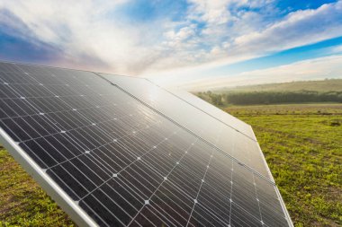 Mavi gökyüzü arkaplanındaki güneş paneli. Yeşil çimenler ve bulutlu gökyüzü. Alternatif enerji kavramı