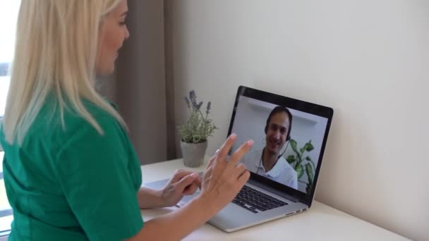 Μια κυρία χαιρετάει τους συναδέλφους της κατά τη διάρκεια μιας τηλεδιάσκεψης. Συνάντηση σε απευθείας σύνδεση, απομακρυσμένη εργασία χρησιμοποιώντας videocall — Αρχείο Βίντεο