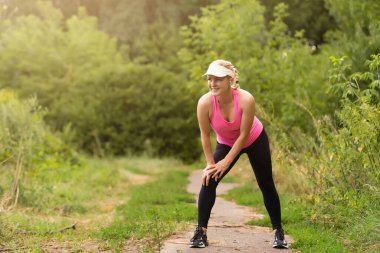 Genç sporcu kadın koşucu şehre koşmadan önce bacaklarını açıyor.