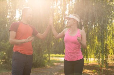 Genç çift, bir kır yolu, egzersiz ve zindelik konsepti üzerinde koşarken sağlıklı bir yaşam tarzının keyfini çıkarıyor.
