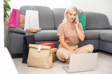 Kredi kartı kullanan bir kadın evde online alışveriş yapıyor.