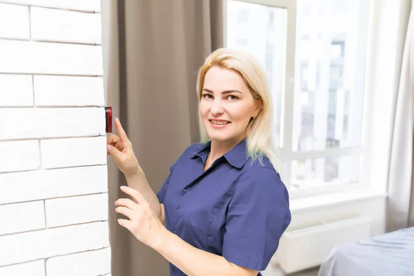 Женщина нажимает на кнопку прикрепленного к стене термостата дома с цифровым дисплеем, показывающим температуру. Концепция изображения для счета за электричество, отопление, охлаждение, экологически чистые, экономия и т.д. — стоковое фото
