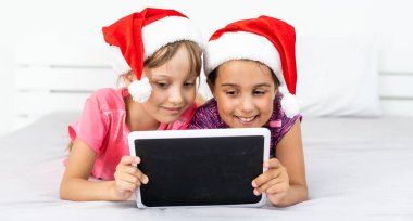 Yeni yıl konsepti. Noel, Noel, Noel, kış, mutluluk konsepti. Tabletle oynayan iki sevimli kız.