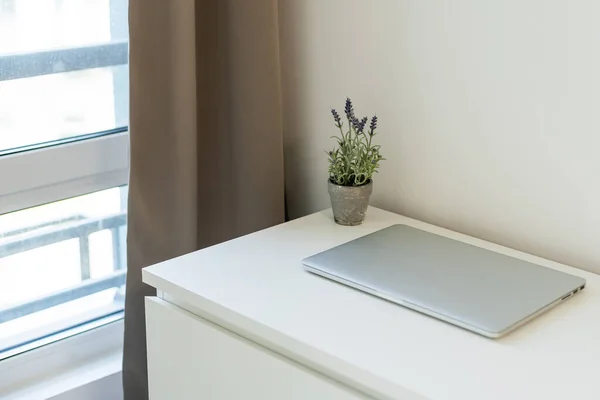 Workspace with laptop closed, on white table with white wall background — 스톡 사진