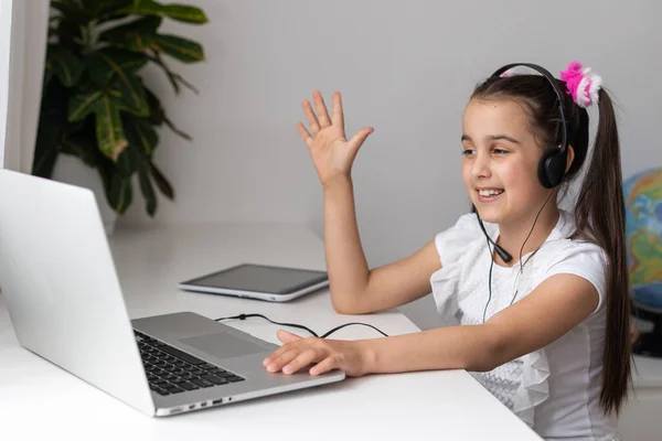 Una giovane ragazza sta frequentando la scuola o le classi online. Studiare in isolamento come scuole chiuse a causa di Covid-19. Ruolo della tecnologia durante l'isolamento nazionale. Imparare a casa concetto — Foto Stock