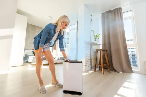 Attractive woman with air purifier in the modern home. — Stock Photo, Image