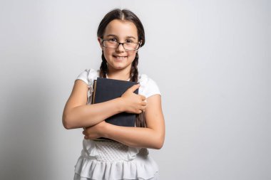 Esmer küçük kız, beyaz arka planda izole edilmiş bir kitap okuyor.