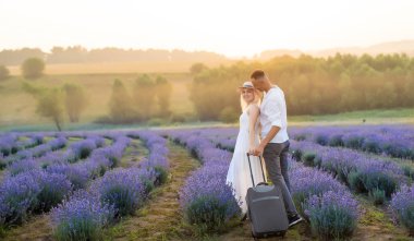 Gülümseyen genç çift lavanta tarlasında el ele tutuşuyorlar, yürüyorlar..