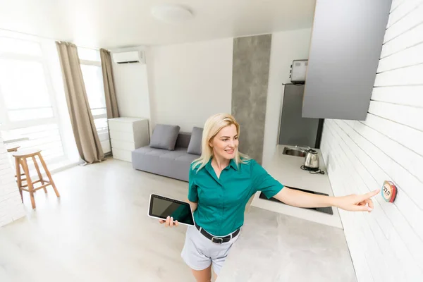 Primer plano de la mujer que ajusta el control central de calefacción digital montado en la pared del termostato en el hogar — Foto de Stock