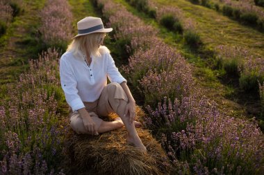 Lavanta tarlasında duran genç bir kadın ve arka planda gün doğumu.