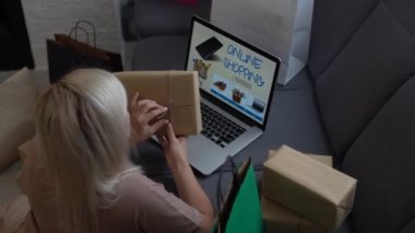Genç kadın satıcı ya da çevrimiçi mağaza çalışanı elinde paket kutusu ile ekommerce postasını kontrol ediyor çevrimiçi perakende satışı ve ticaret mağazası siparişi teslimat deposunda dizüstü bilgisayar kullanarak tamamlanıyor..