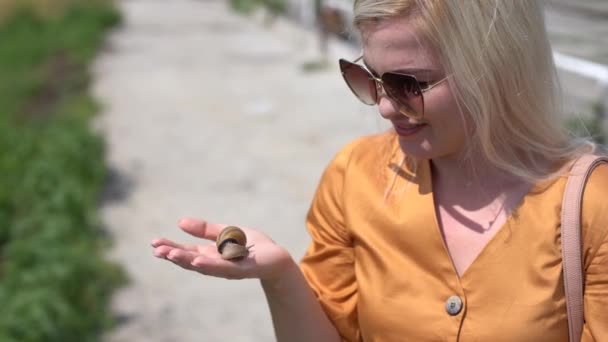 Közelkép egy csigát tartó fiatal nőről, aki a farmon gondozza őket a csigáknak. — Stock videók