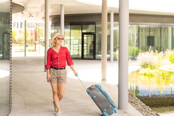 Gezgin bavulu, seyahat yerinde bavul taşıyan bir kadın. Tatil gezisinde mercek fişeği tekniği, tatil kavramlarında seyahat. — Stok fotoğraf