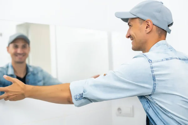 Handyman installeren spiegel in de badkamer. — Stockfoto