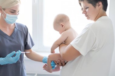 Çocuk doktoru küçük çocuğa aşı yapıyor.