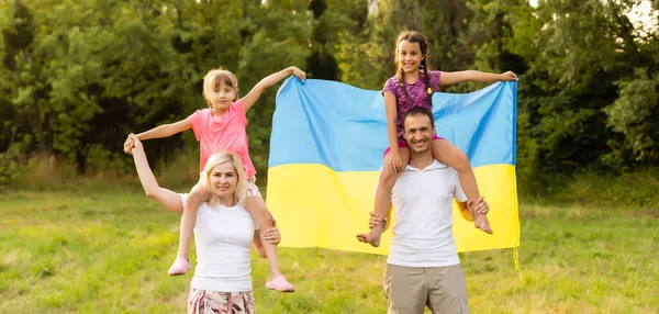 Família feliz com bandeira de ucraniano no campo. estilo de vida — Fotografia de Stock