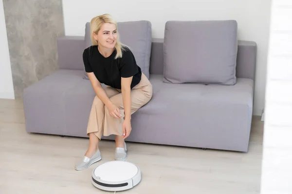 Modernt liv koncept, kvinna avkopplande, automatisk robotsvävare städa rummet medan — Stockfoto