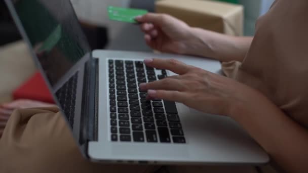 Lachende vrouw met laptop en creditcard thuis. Meisje met laptop en bankkaart binnen. Mooie vrouw ligt in de woonkamer online winkelen met creditcard. Eenvoudig betalen met behulp van digitale gadget. — Stockvideo