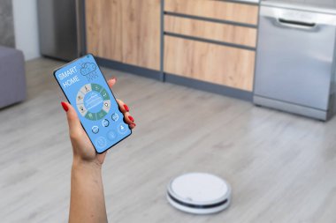 Telefondaki akıllı ev kontrolü. Kadın eli telefon. Oturma odası arka planda.