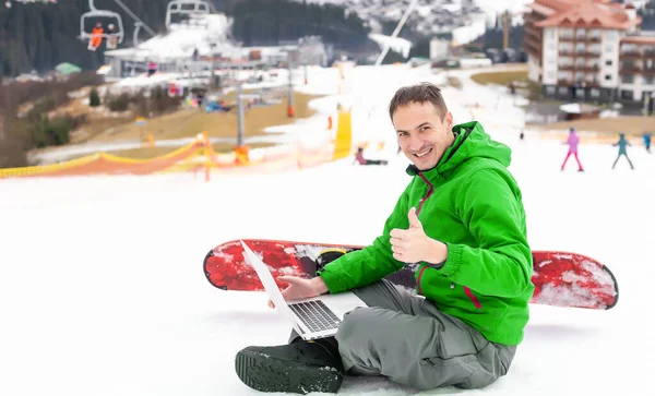 Чоловічий сноубордист використовує ноутбук на засніженому гірському ландшафті — стокове фото