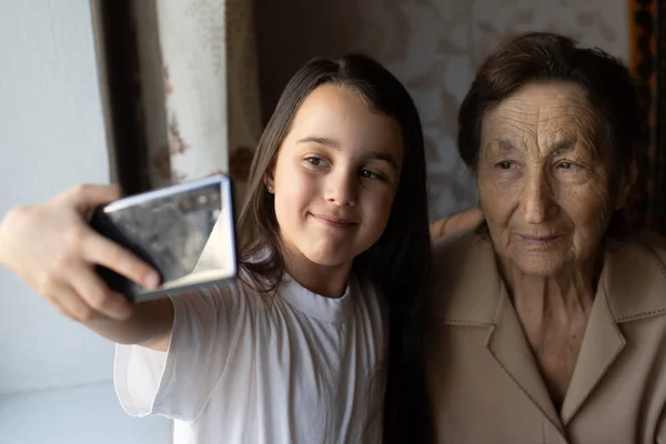 Бабуся і онучка. Мила дівчинка показує бабусі смартфон.. — стокове фото