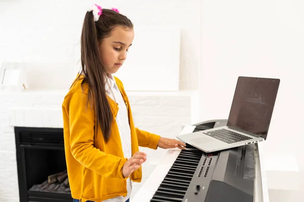 Kleines Mädchen beobachtet Online-Lektion Tutorial, wie man einen Synthesizer lernt — Stockfoto