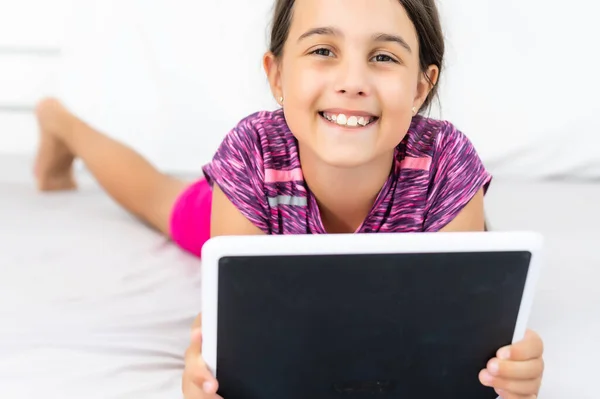 Otthon, szabadidő, új technológia és zenei koncepció - mosolygós kislány táblagéppel és fejhallgatóval otthon — Stock Fotó
