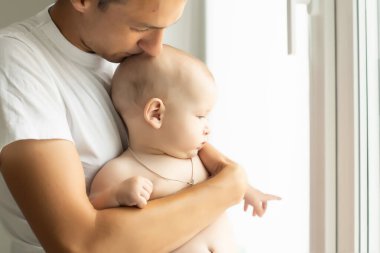 Gülümseyen bir genç adam kucağında 6 aylık bir bebek