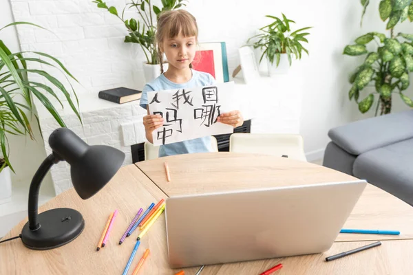 stock image little girl learning chinese while using her laptop computer in the living room at home. family activity concept.